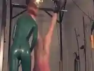 Dominating redhead flogging sub in a bodysuit