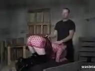 Blonde sex slave in fishnet dress gets spanked and flogged by her Master