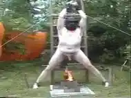 Chained naked male slave gets his cock and balls roasted